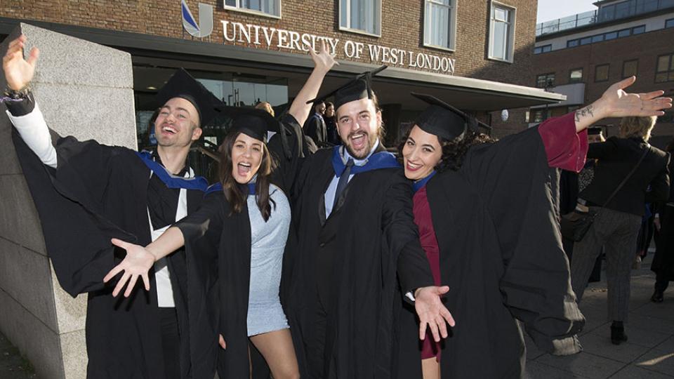 Four graduates celebrating outside the University of West London