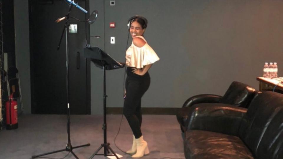Norleen Taban standing next to a microphone and stand in a recording studio
