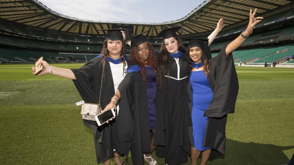 Four UWL graduates celebrating on the pitch of Twickenham Stadium