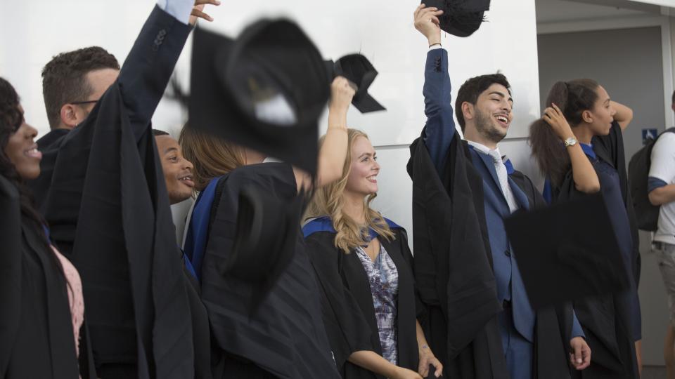 Graduates celebrating graduating as they hold their hats.