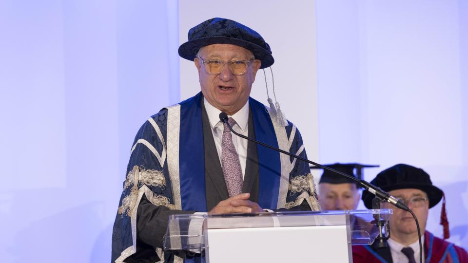 Sir Laurence Geller CBE standing at the graduation ceremony accepting an honorary award.