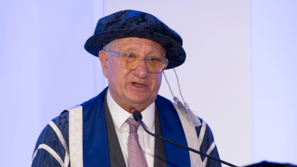 Sir Laurence Geller CBE standing at the graduation ceremony accepting an honorary award.