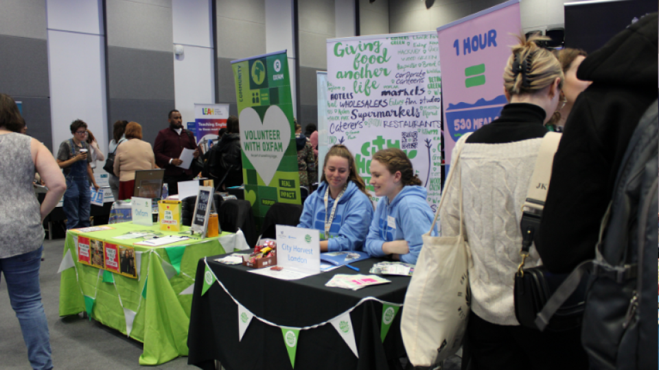 Two people sitting at the City Harvest London stand at the volunteering fair.