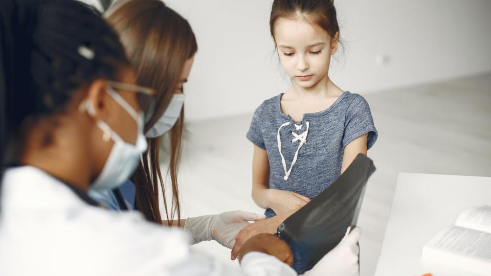 Child having blood pressure taken by two female doctors