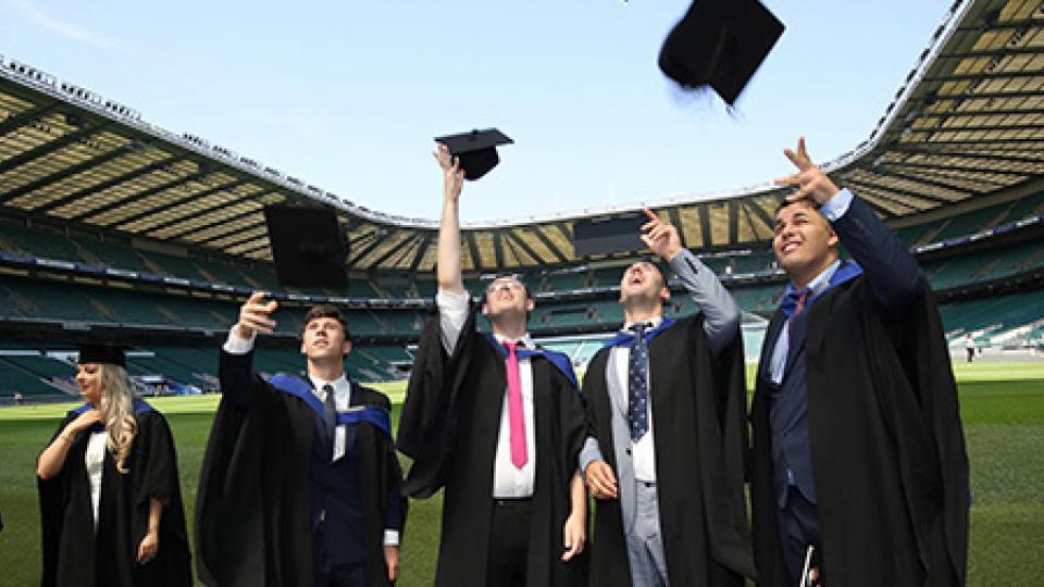 Graduates in gowns celebrate at Twickenham Stadium