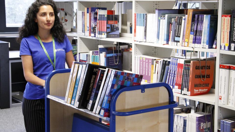 Library staff pushing book trolley