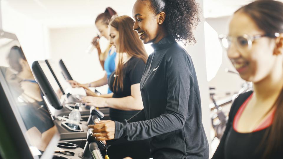People exercising on a cross trainer in a gym.