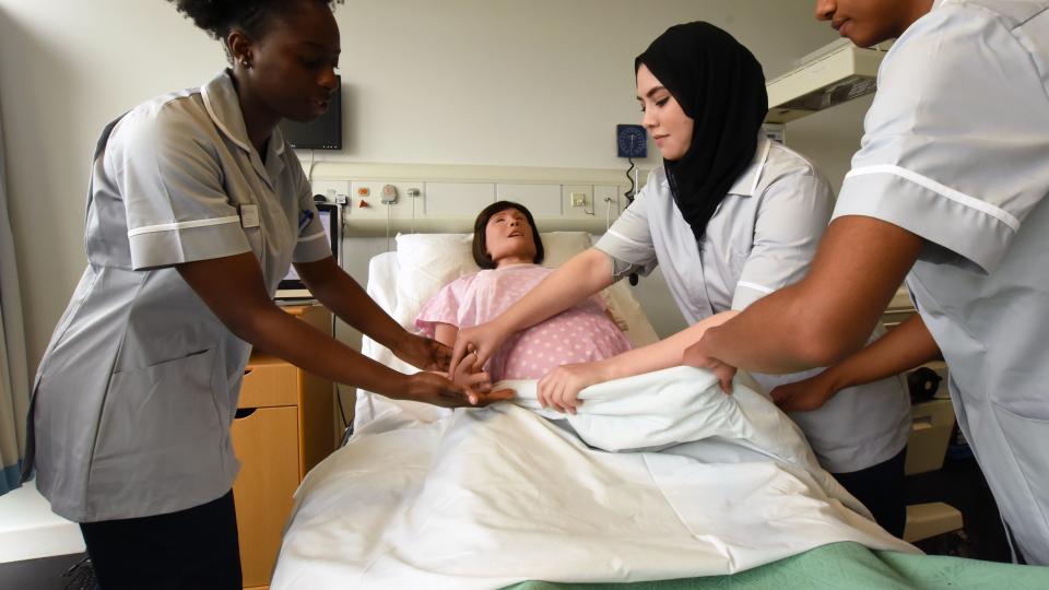 Student nurses surround practice midwifery skills on a dummy
