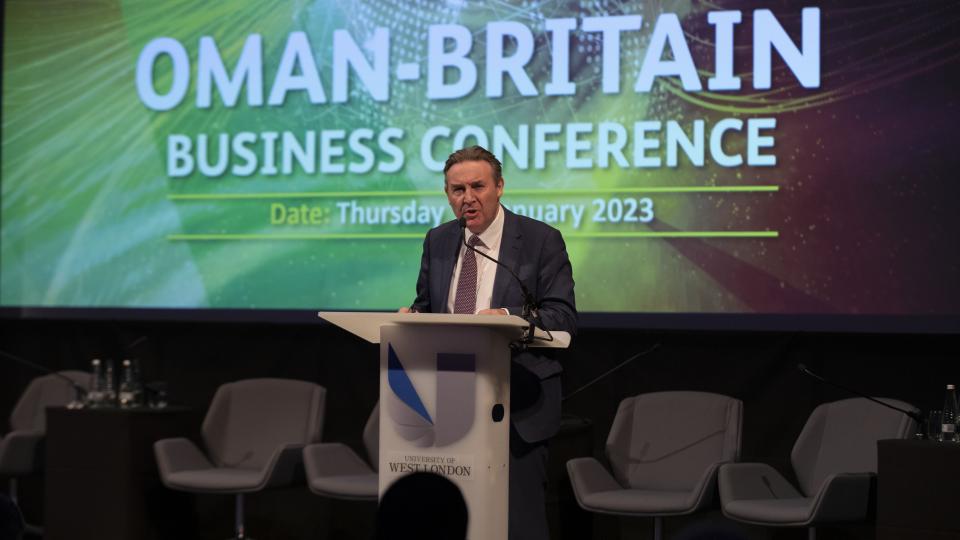 Vice Chancellor Professor Peter John CBE talking at the Oman-Britain Business Conference on stage with the Oman-Britain Business Conference projection behind him.