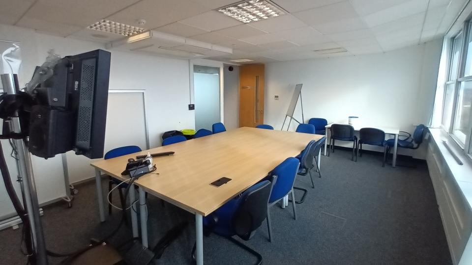 A meeting room at Fountain House, equipped with a large table, several chairs, a presentation screen and whiteboard