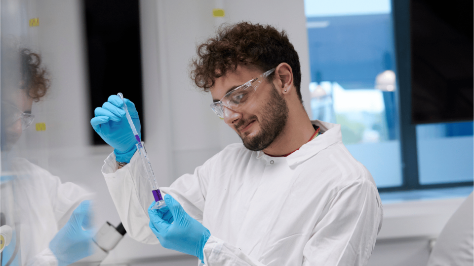 A biomedical student holding a pipette in a lab