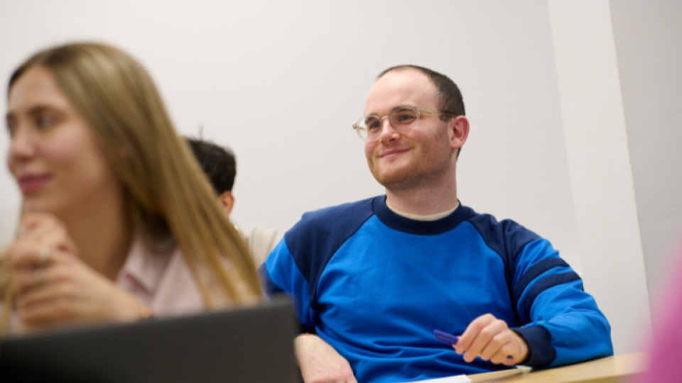 A student in a blue sweatshirt smiling during group study.