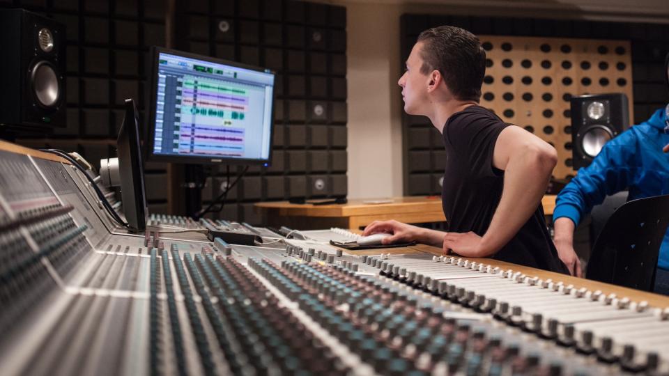 A music student sits behind a mixing desk
