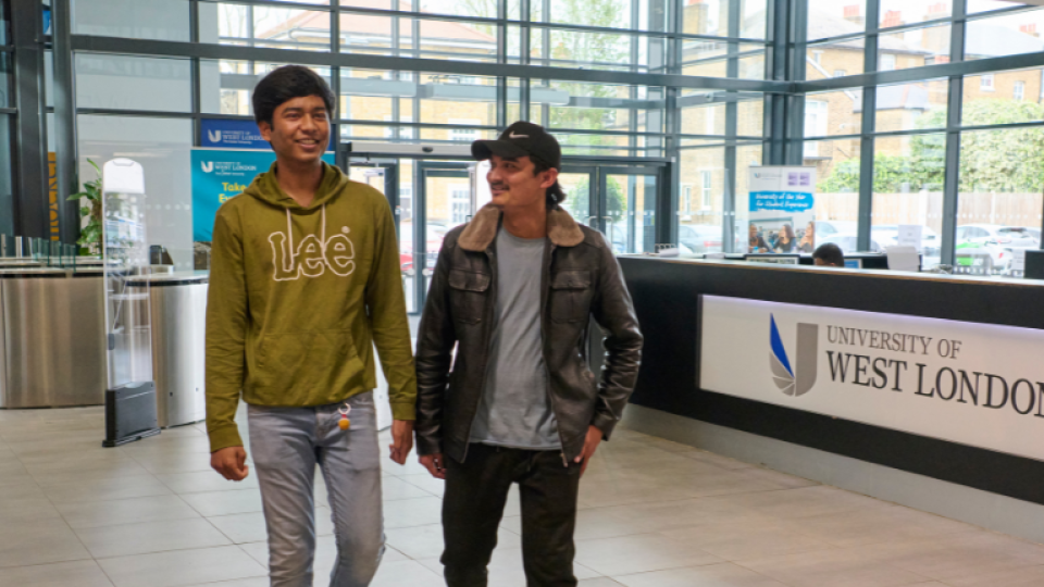 Two students walking through reception at the University of West London