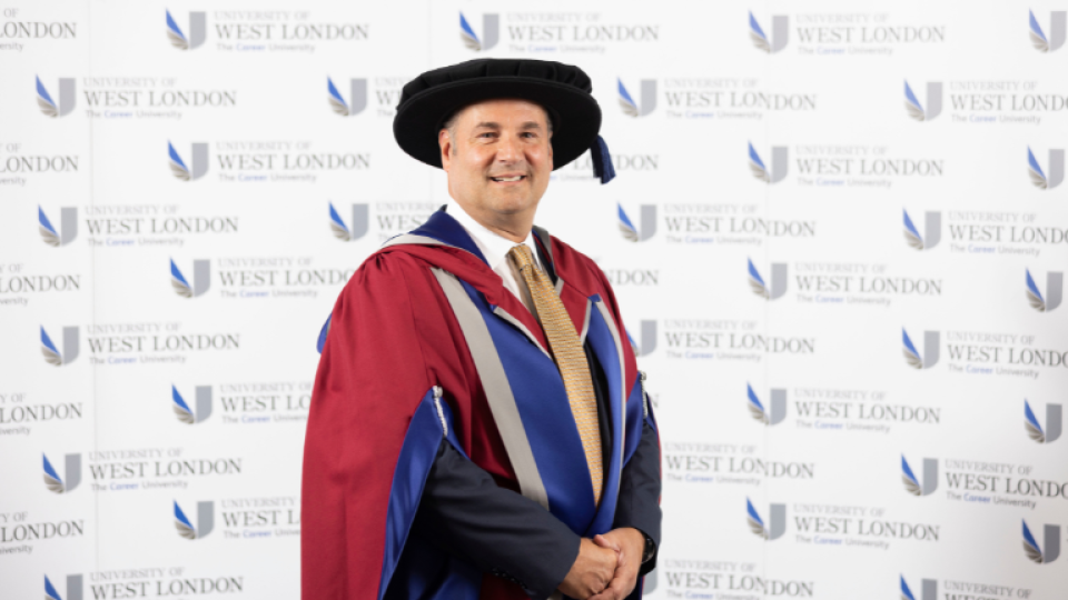 Anthony Capuano is standing with his gown and hat on to camera.