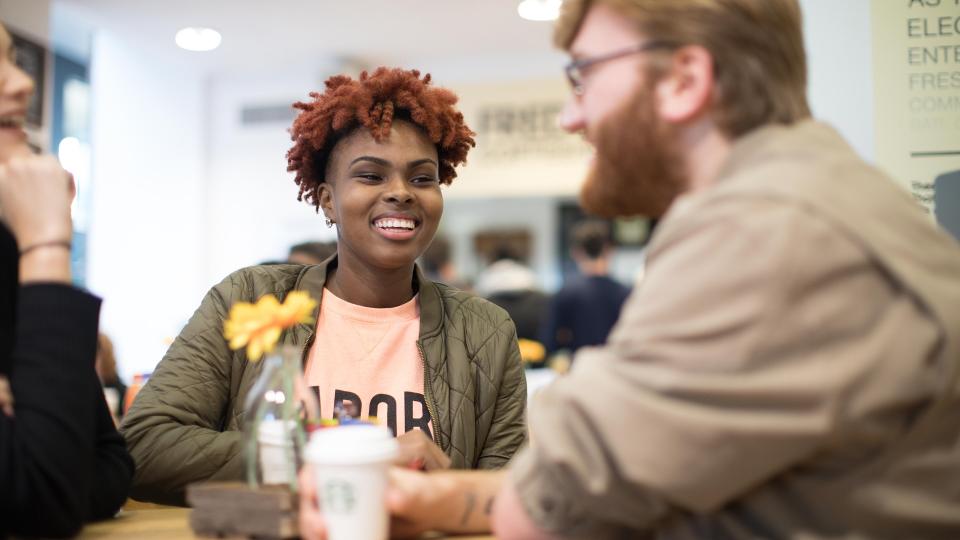 Three people sitting at a table drinking coffee