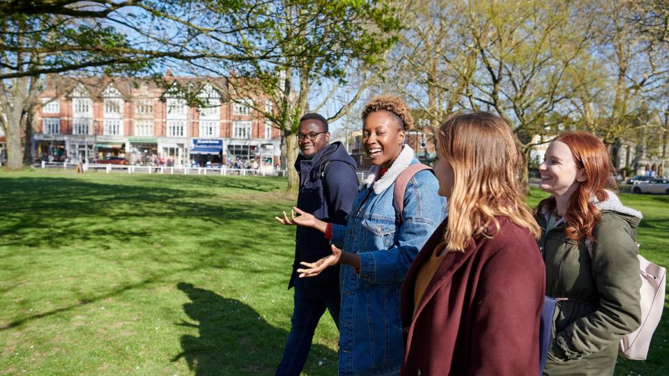 A group of four students walking through a park and chatting.