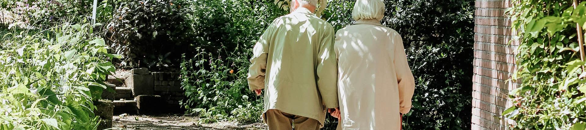 two older people walking in a care home garden