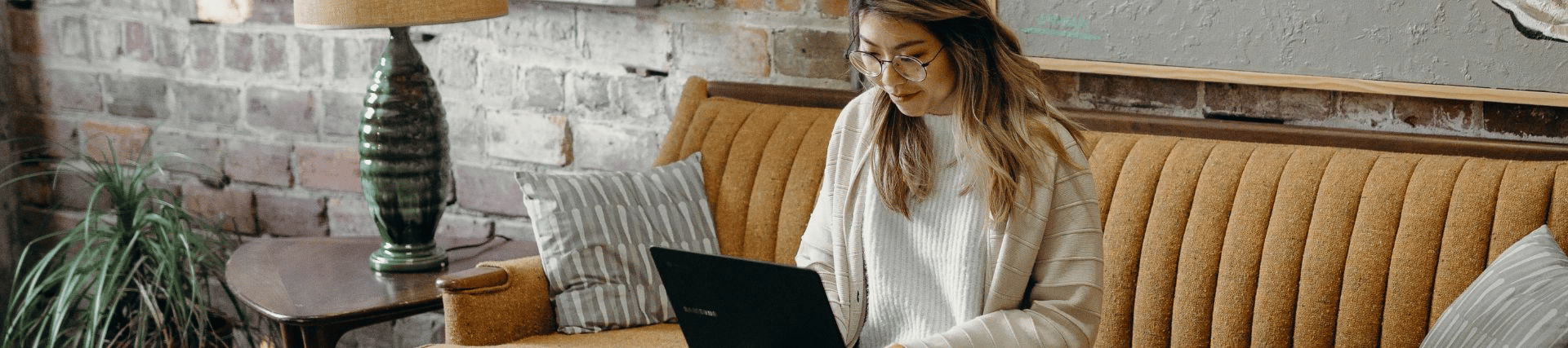 A student studying at home with her laptop in a lounge setting. 