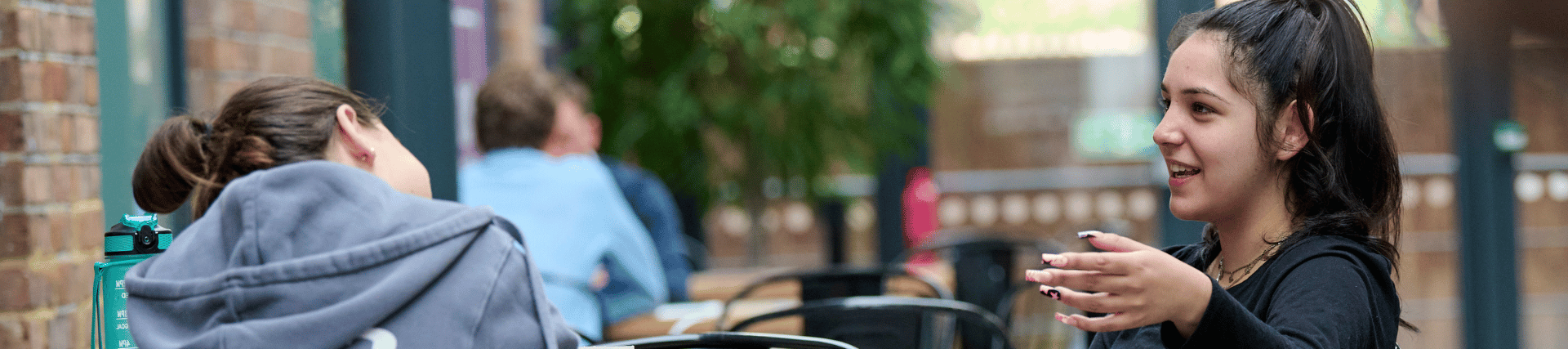 A student gesturing with her hand whilst in conversation.