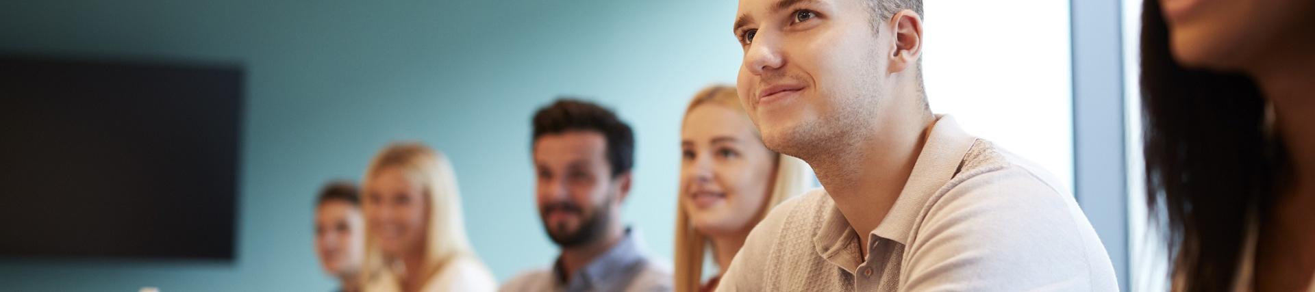 A group of smiling students listen to a lecture