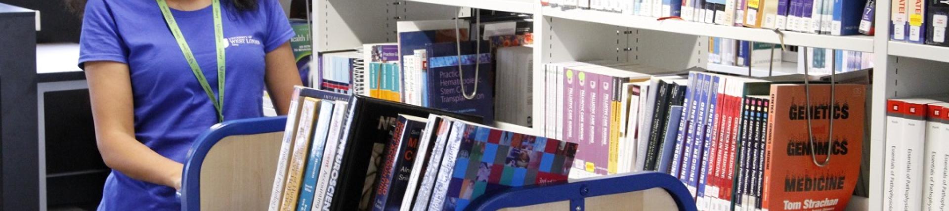 Library staff pushing book trolley