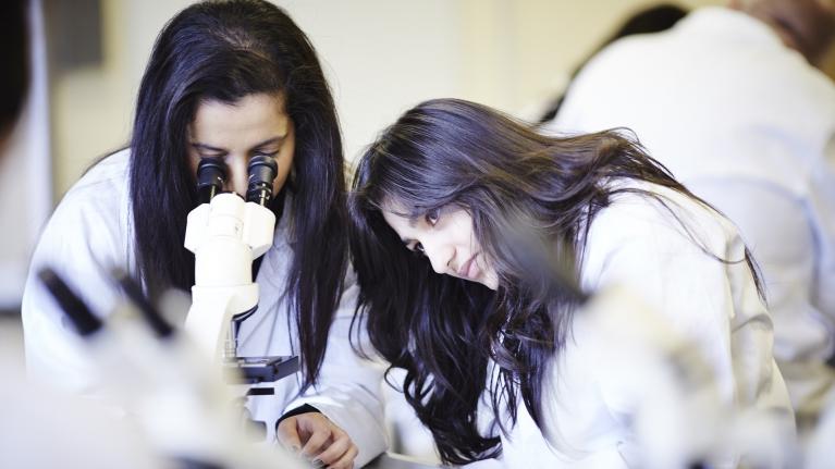 Two forensic science students with a microscope